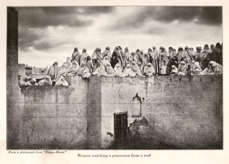 Women watching a procession from a roof.